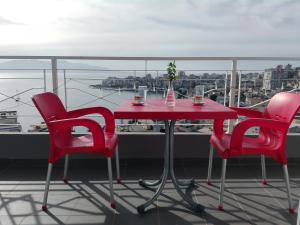 a red table and four chairs on a balcony at Luxury Apartment Krisi Sarandë in Sarandë