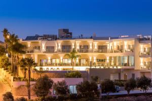 a large white building with palm trees in front of it at Caneiros Luxury House & Suites in Ferragudo