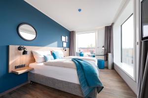 a bedroom with a large bed with a blue wall at HARBR. hotel Konstanz in Konstanz