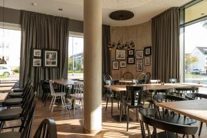 a restaurant with wooden tables and chairs and windows at HARBR. hotel Konstanz in Konstanz