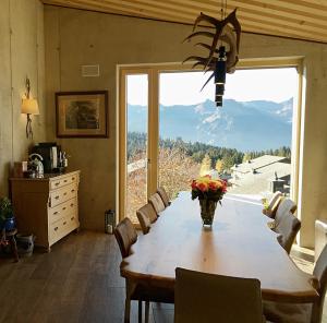 jadalnia ze stołem i dużym oknem w obiekcie Mountain Chalet Amden w mieście Amden