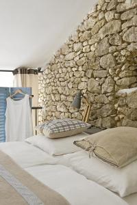 a bedroom with two beds and a stone wall at Bassiviere Barn Chic in Saint-Étienne-de-Villeréal