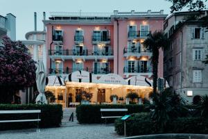 a large pink building with benches in front of it at Art Hotel Tartini in Piran