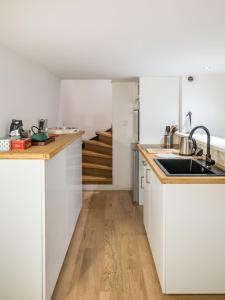 a kitchen with white cabinets and a sink at Honorê - Suite Vaubecour in Lyon