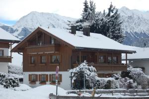 a building covered in snow with mountains in the background at Ferienwohnungen Alpentraum - Pusteblume in Obermaiselstein