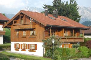 a wooden house with a red roof at Ferienwohnungen Alpentraum - Pusteblume in Obermaiselstein +7 photos