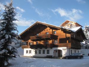 a large wooden building with a car parked in the snow at Apartmenthaus Kuchelberg in Altenmarkt im Pongau