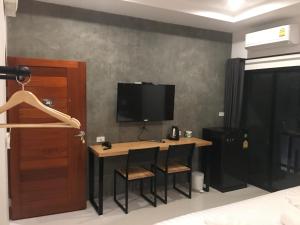 a room with a desk with two chairs and a television at Beloft Hotel in Nakhon Si Thammarat