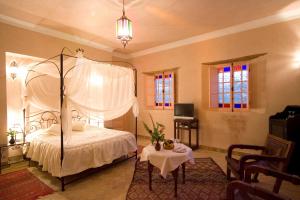 a bedroom with a canopy bed and a table at Hotel Dar Zitoune Taroudant in Taroudant