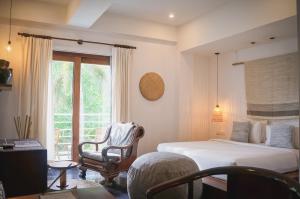a bedroom with a bed and a chair and a window at iRoHa Garden Hotel & Resort in Phnom Penh