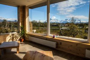 Habitación con ventanas grandes, mesa y banco. en PAMPA HOSTEL, en Torres del Paine