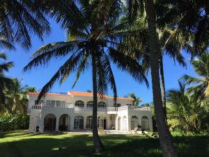una gran casa blanca con palmeras en el primer plano en Baoba Breeze Bed & Breakfast- beachfront paradise, en Cabrera