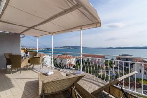 balcone con tavoli, sedie e vista sull'acqua di La Bodega Apartments a Trogir
