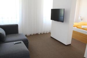 a living room with a tv and a couch and a bed at Hotel Albis in Vrchlabí