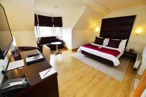 a bedroom with a bed and a desk with a computer at Glynhill Hotel & Spa near Glasgow Airport in Renfrew