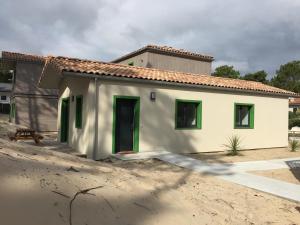 a small white house with green doors in a yard at Villa Nature in Lacanau-Océan