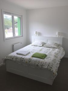 a white bedroom with a bed with a window at Villa Nature in Lacanau-Océan