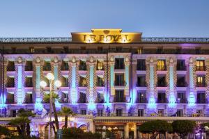 un edificio illuminato di notte con luci blu di Hôtel Le Royal Promenade des Anglais a Nizza