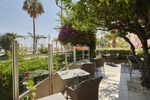 a restaurant with tables and chairs under a tree at Hôtel Le Royal Promenade des Anglais in Nice