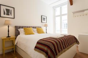 a white bedroom with a large bed with yellow pillows at Baixa Downtown by Central Hill Apartments in Lisbon