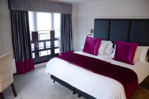 a bedroom with a large bed with purple pillows at Glynhill Hotel & Spa near Glasgow Airport in Renfrew