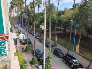 a street with cars parked in a parking lot with palm trees at Appart 2 Mars Casablanca in Casablanca
