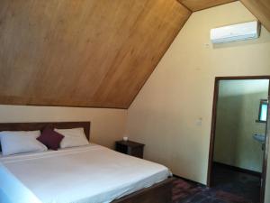 1 dormitorio con cama y techo de madera en Pondok Anjani, en Gili Meno