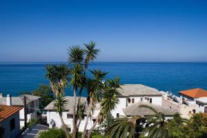 a group of buildings and palm trees in front of the ocean at Panagopoulos House in Agios Ioannis Pelio