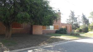 una casa de ladrillo con un árbol delante de ella en Homero y Martín Coronado en Villa Carlos Paz