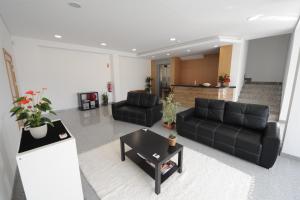 a living room with two black couches and a table at Senhor dos Perdoes Alojamento Local in Ribeirão