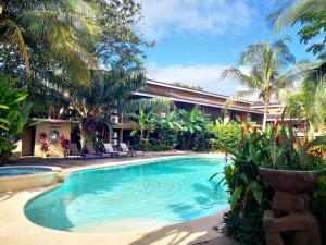 a swimming pool in front of a building with palm trees at Cabo Velas Estates in Playa Grande