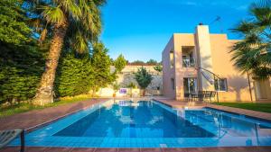 a swimming pool in front of a house at Meliades Villas in Agia Marina Nea Kydonias