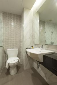 een badkamer met een wastafel, een toilet en een spiegel bij Paragon Grand Resort in Jomtien Beach