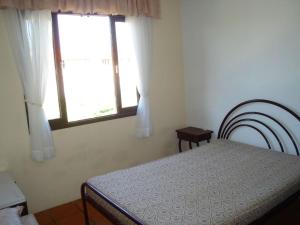 1 dormitorio con cama y ventana en Seu lugar no paraiso... 150 metros da praia central, en Bombinhas