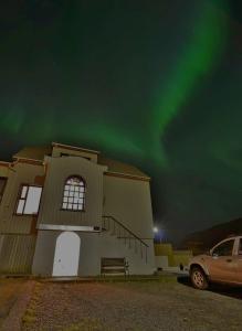 a building with a green sky with a car parked in front at Kósý Vík in Vík