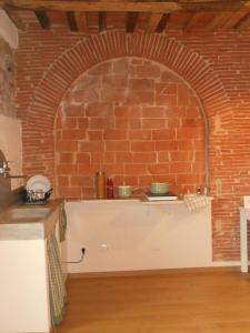 una cocina con una pared de ladrillo y 2 ollas en un estante en Appartamento URANIA - LE MUSE en Pietrasanta