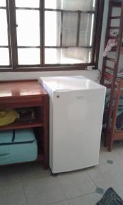 a small white refrigerator in a room with a desk at Los metates in Zipolite