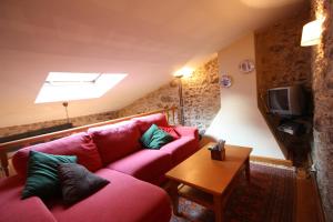 ein Wohnzimmer mit einem roten Sofa und einem Tisch in der Unterkunft Vivienda Vacacional Vila Castriño en las Rias Baixas in Tarragona