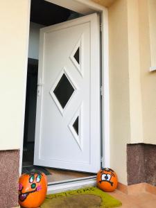 Due zucche sedute davanti a una porta bianca. di Kókusz Apartmanok a Eger