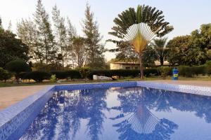une piscine bleue avec un palmier en arrière-plan dans l'établissement Yuna Village Garden Resort, à Tubaya