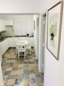 een keuken met een tafel, witte kasten en een tegelvloer bij Apartamento Efigenia vista Mar in Valle Gran Rey