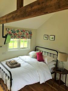 a bedroom with a bed with white sheets and red pillows at The Parcel Shed in Gilling East