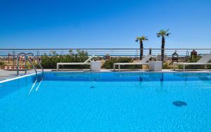 ein großer Pool mit Stühlen und das Meer im Hintergrund in der Unterkunft Hotel Delle Nazioni in Caorle