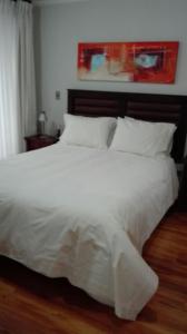 uma grande cama branca com lençóis e almofadas brancos em Austral Rentahome Américo Vespucio Norte em Santiago