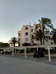 a building with palm trees in front of a parking lot at Apartamento Rey-Piscina in Denia