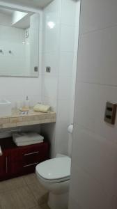 uma casa de banho branca com um WC e um espelho. em Austral Rentahome Américo Vespucio Norte em Santiago