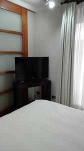 a bedroom with a bed and a flat screen tv at Austral Rentahome Américo Vespucio Norte in Santiago