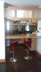 a kitchen with two red bar stools in a kitchen at Austral Rentahome Américo Vespucio Norte in Santiago