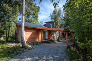 una pequeña cabaña en el bosque con un árbol en Casa Las Lilas, en Villa La Angostura