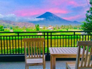 two chairs and a table on a balcony with a mountain at D'uma Amed Homestay in Amed